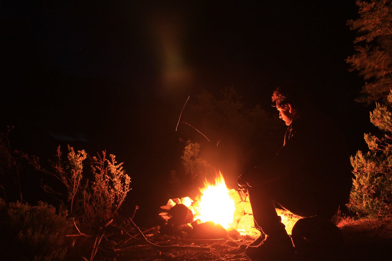 Man sitting by campfire at night — the essence of self-reliance